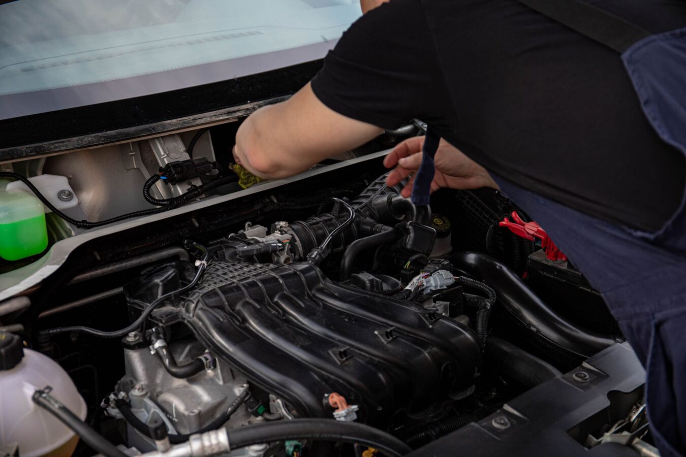 mechanic inspecting valve cover gasket leak with flashlight on engine