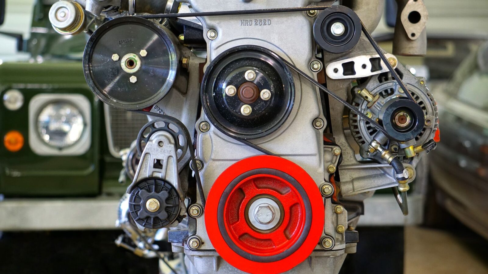 mechanic inspecting car AC compressor clutch and pulley with feeler gauge
