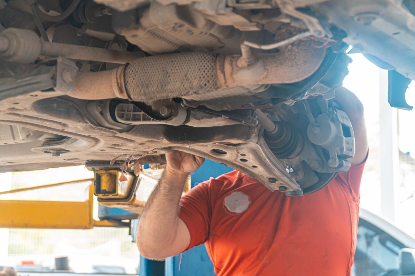 mechanic replacing rear shock absorber on vehicle lift