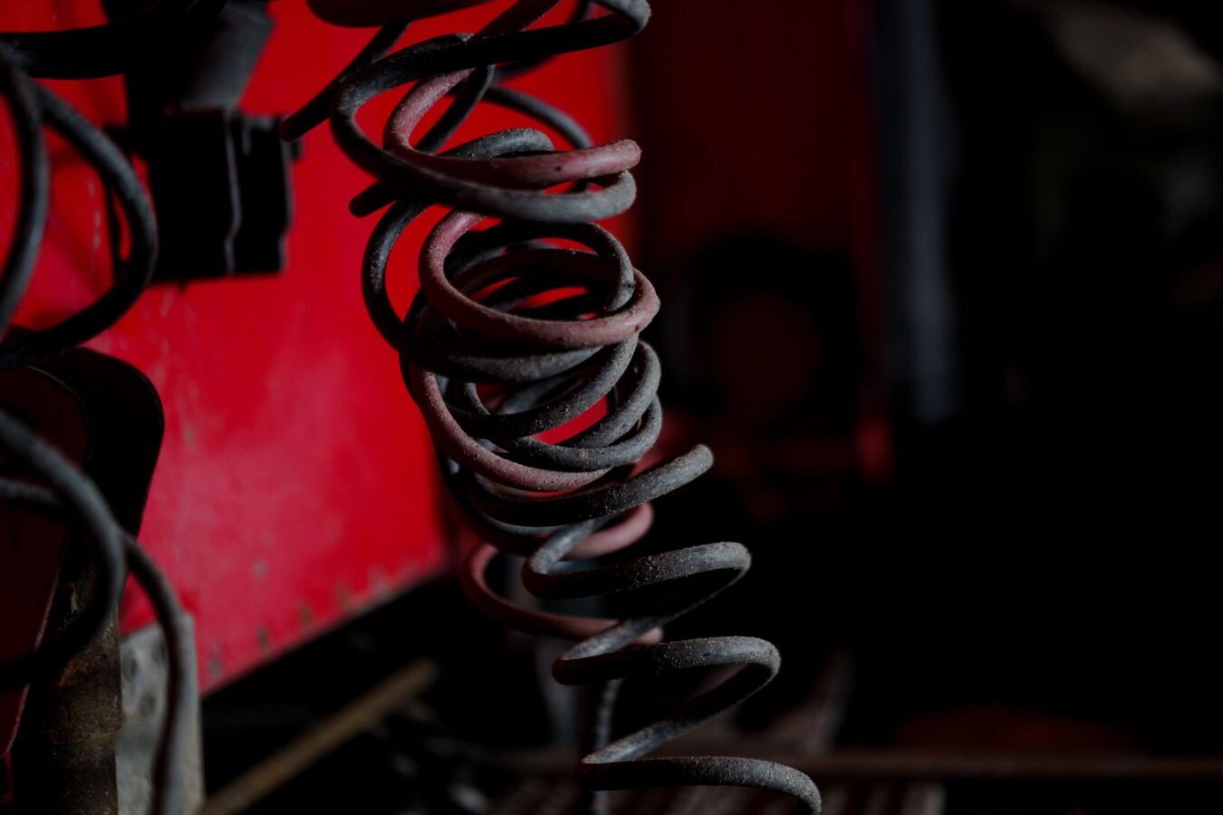 mechanic using coil spring compressor tool in workshop