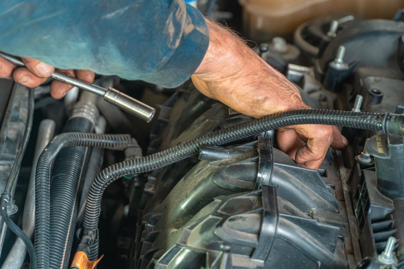 mechanic replacing car air conditioning receiver drier with torque wrench