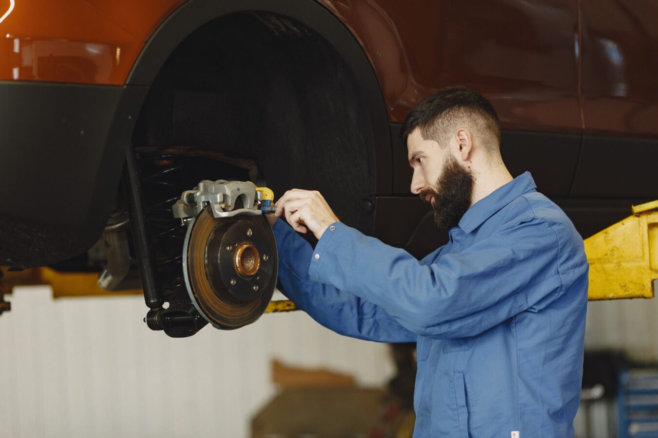 mechanic installing new brake pads on car caliper