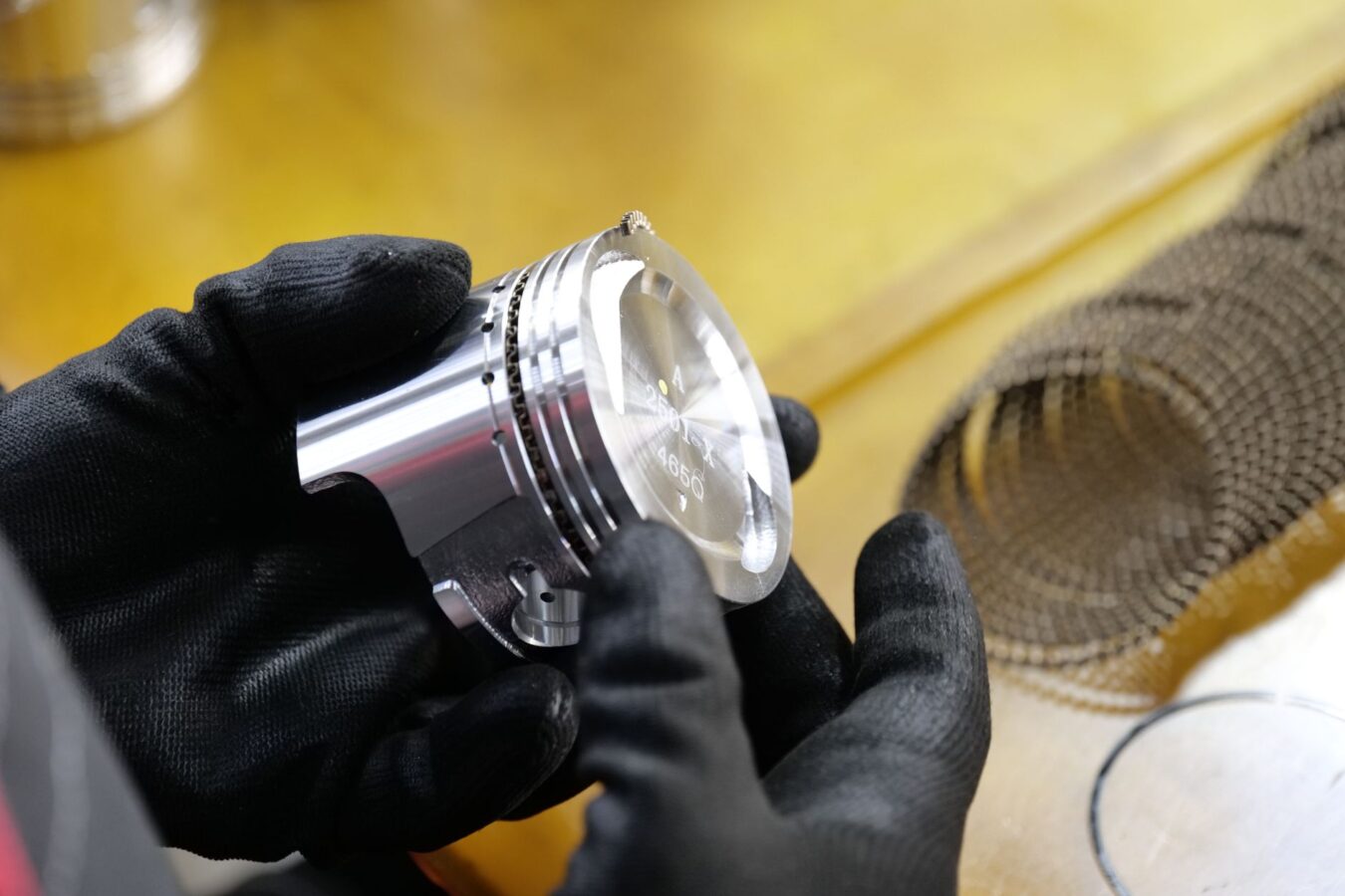 mechanic using micrometer to measure piston skirt diameter in workshop