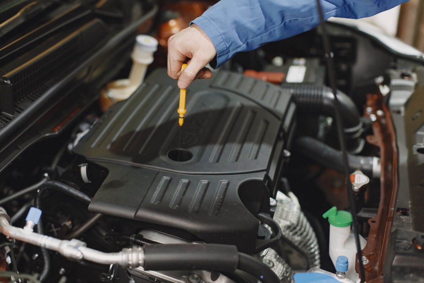 car engine bay with oil dipstick handle visible